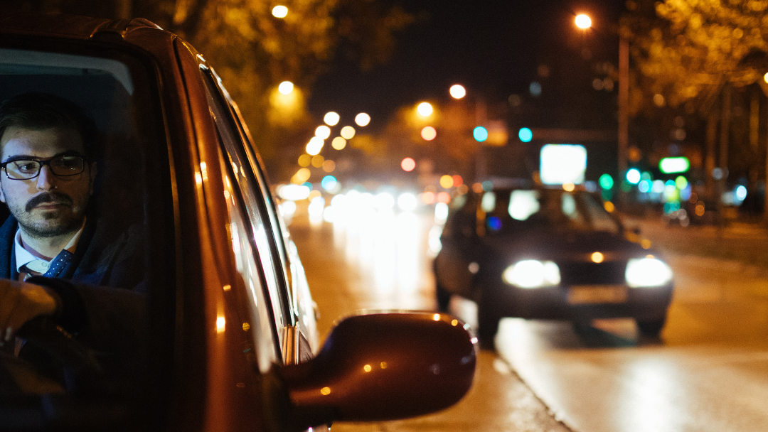 A young driver practicing night driving on a dimly lit Ontario road