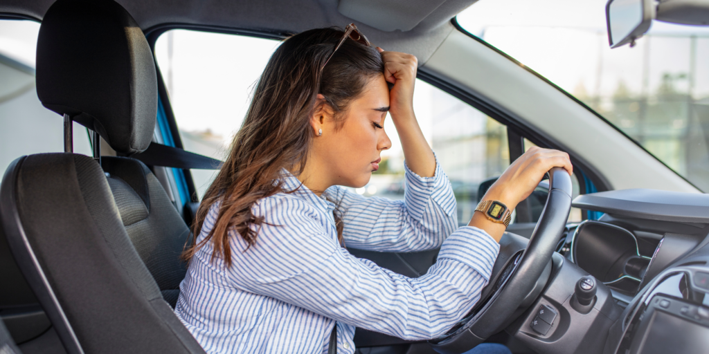 A woman experiencing stress while sitting behind the wheel of a car, gripping the steering wheel tightly