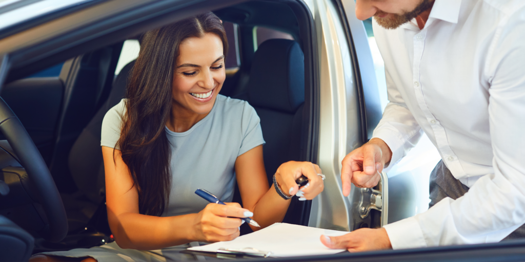 A young driver inspecting a used car with a mechanic in Ontario, debating between new and used car options.